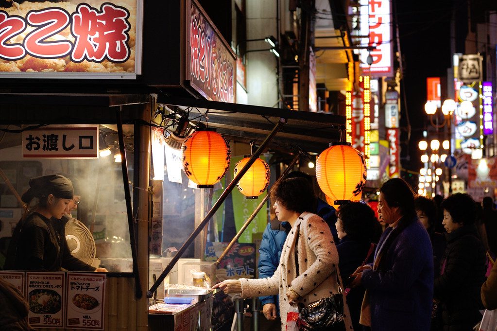 Night market food stall lit with seasonal signage and lanterns
