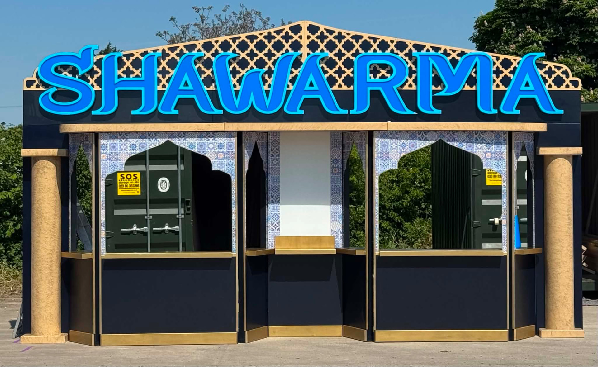 Bespoke shawarma kiosk with ornate latticework, blue neon lettering and decorative tiled columns