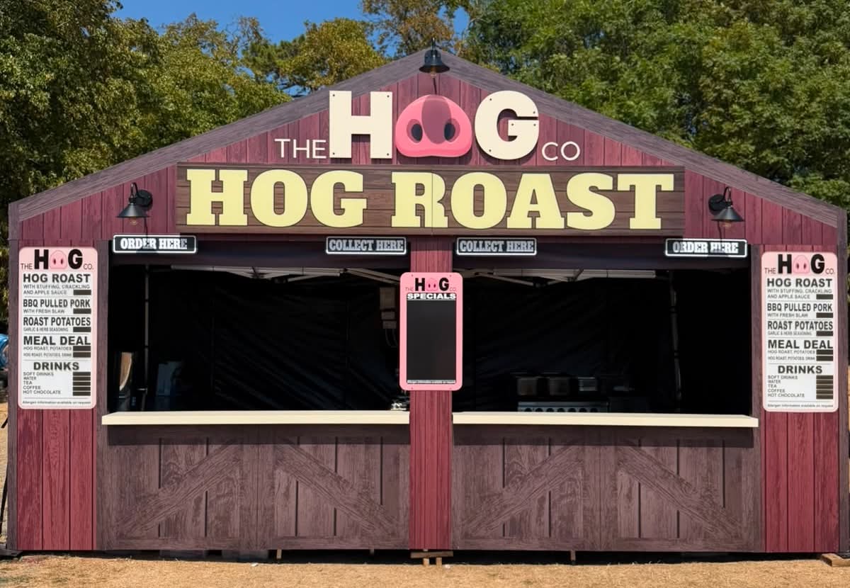 The Hog Roast Co. branded wooden chalet with illuminated Hog Roast lettering and menu boards